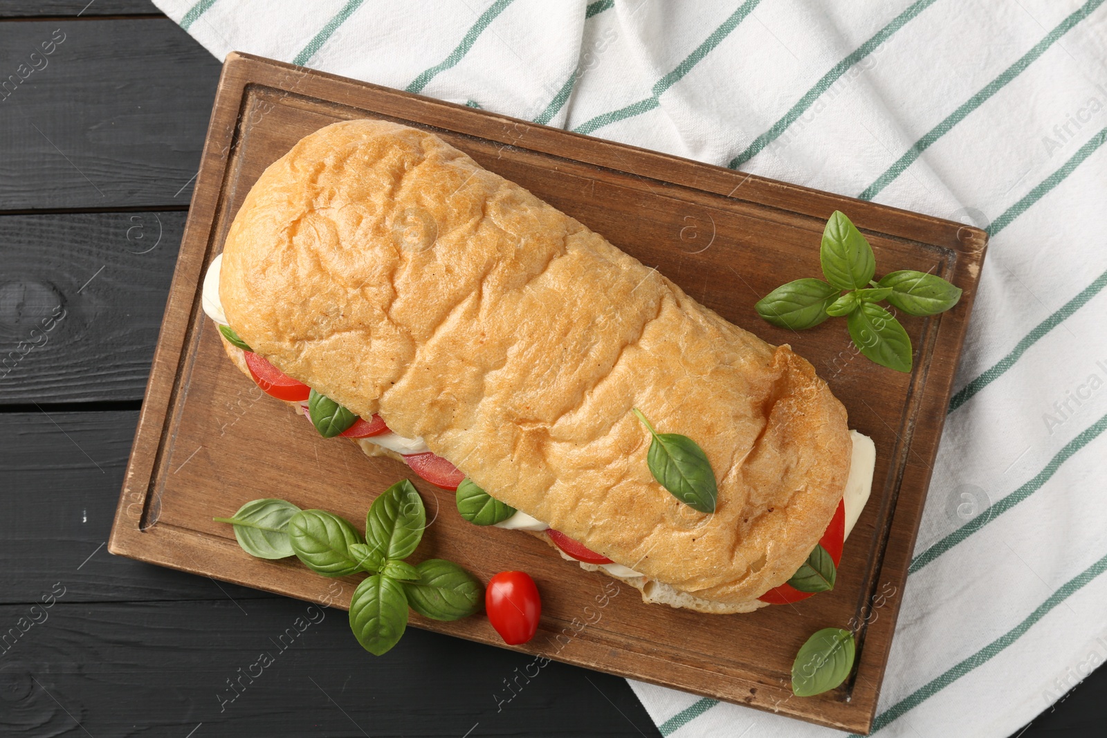 Tasty sandwich with mozzarella cheese, tomatoes and basil on black wooden table, top view Photo of Tasty sandwich with mozzarella cheese, tomatoes and basil on black wooden table, top view
