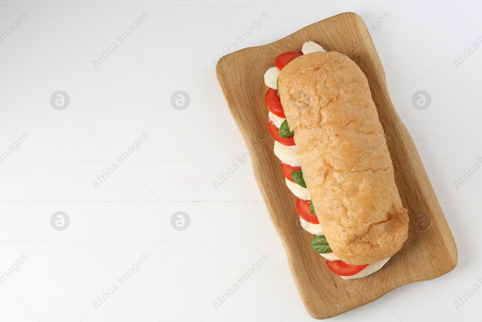 Tasty sandwich with mozzarella cheese, tomatoes and basil on white wooden table, top view. Space for text Photo of Tasty sandwich with mozzarella cheese, tomatoes and basil on white wooden table, top view. Space for text