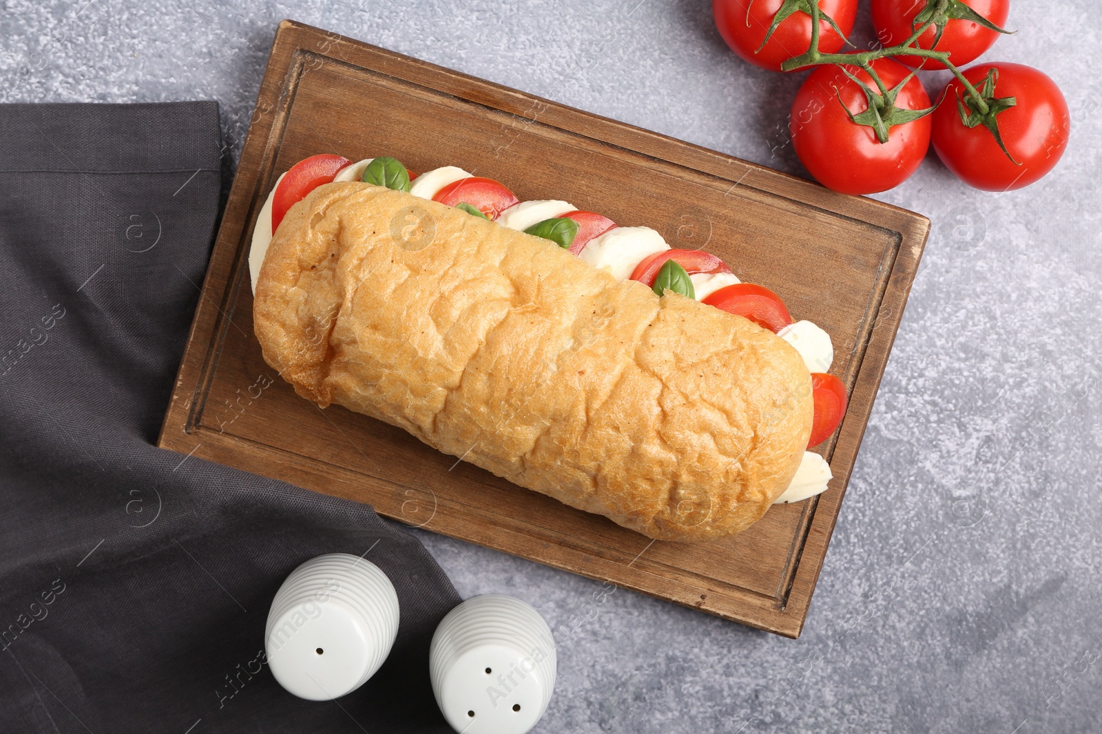 Tasty sandwich with mozzarella cheese, tomatoes and basil on grey textured table, flat lay Photo of Tasty sandwich with mozzarella cheese, tomatoes and basil on grey textured table, flat lay