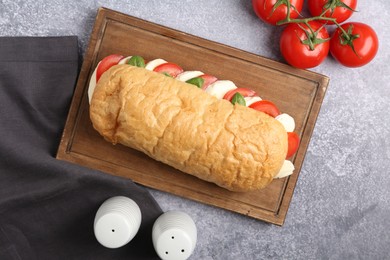 Photo of Tasty sandwich with mozzarella cheese, tomatoes and basil on grey textured table, flat lay