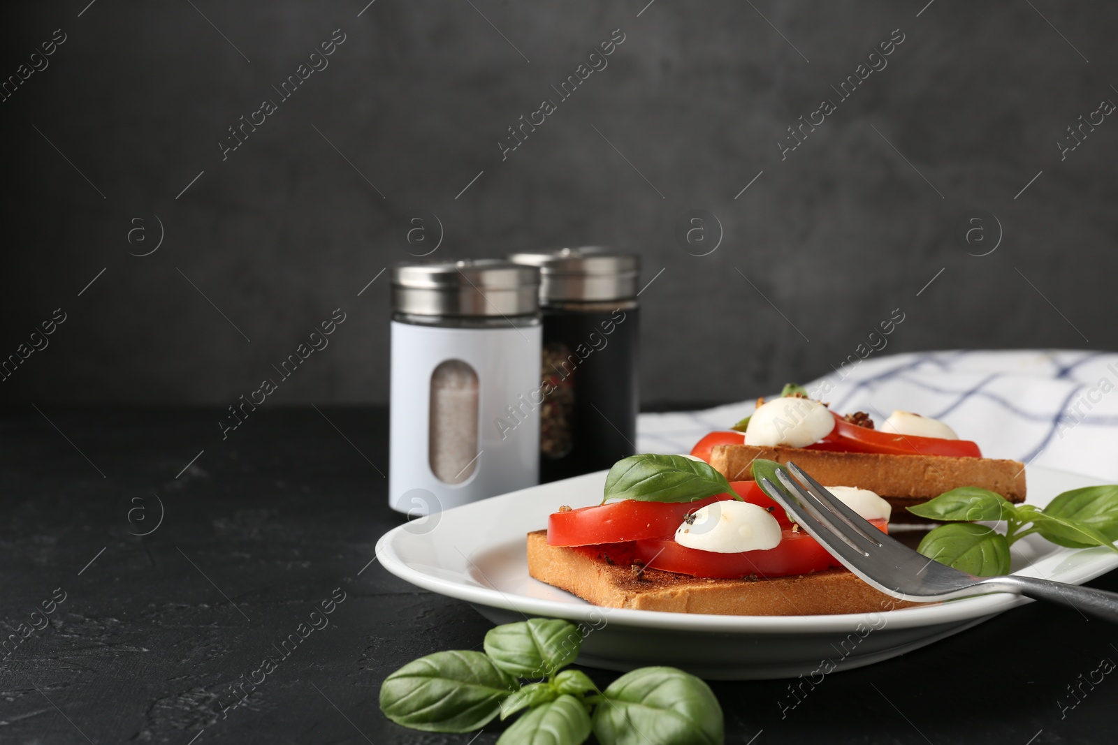 Tasty sandwiches with mozzarella cheese, tomatoes, basil and fork on dark textured table against grey background, closeup. Space for text Photo of Tasty sandwiches with mozzarella cheese, tomatoes, basil and fork on dark textured table against grey background, closeup. Space for text