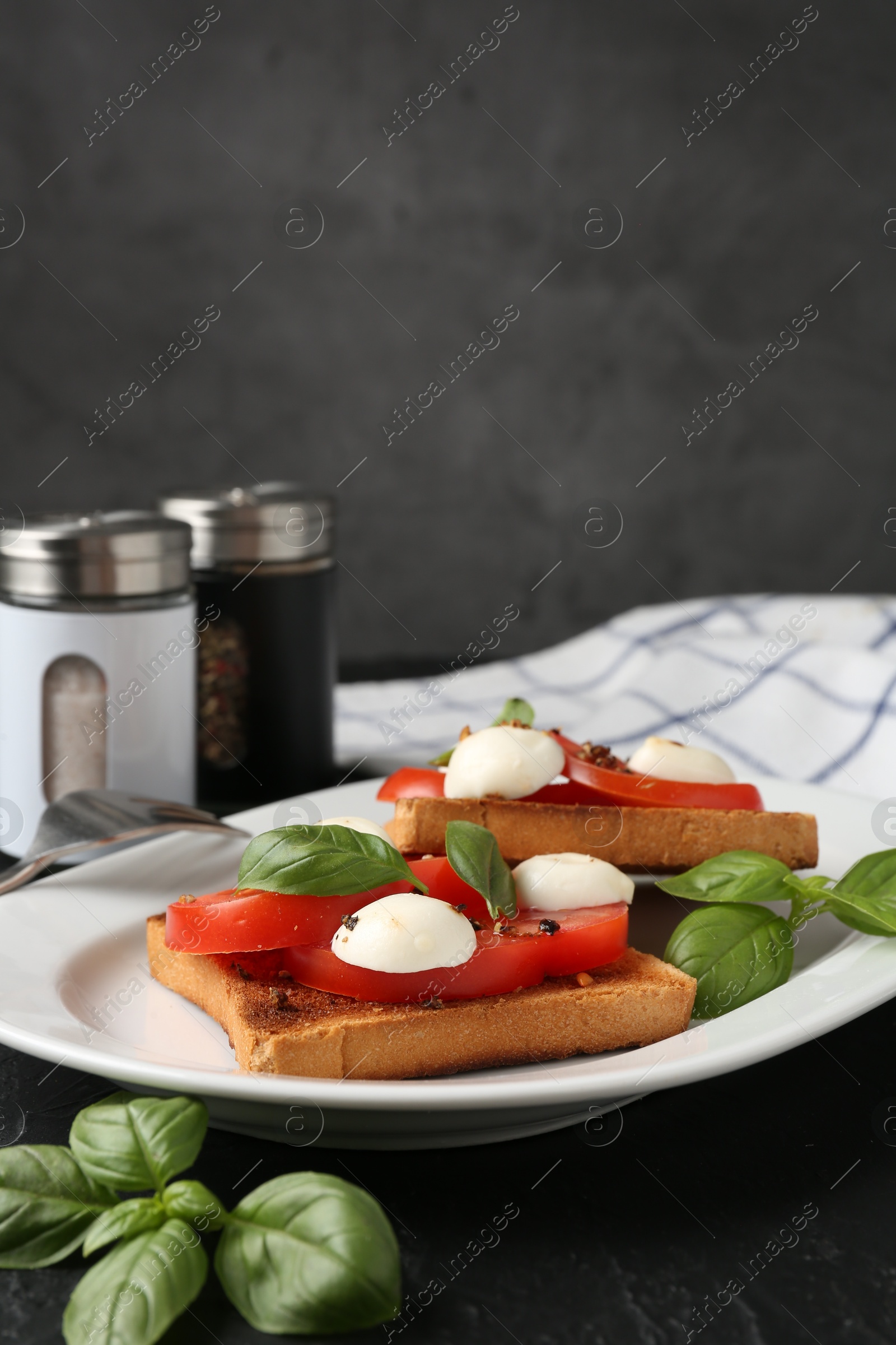 Tasty sandwiches with mozzarella cheese, tomatoes and basil on dark textured table against grey background, closeup Photo of Tasty sandwiches with mozzarella cheese, tomatoes and basil on dark textured table against grey background, closeup