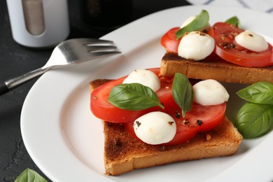Photo of Tasty sandwiches with mozzarella cheese, tomatoes and basil on dark textured table, closeup