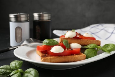 Photo of Tasty sandwiches with mozzarella cheese, tomatoes and basil on dark table against grey background, closeup