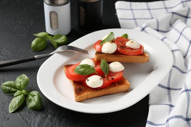 Photo of Tasty sandwiches with mozzarella cheese, tomatoes and basil on dark textured table, closeup