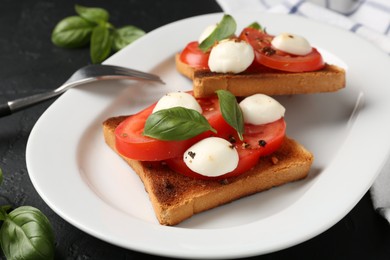 Photo of Tasty sandwiches with mozzarella cheese, tomatoes and basil on dark textured table, closeup