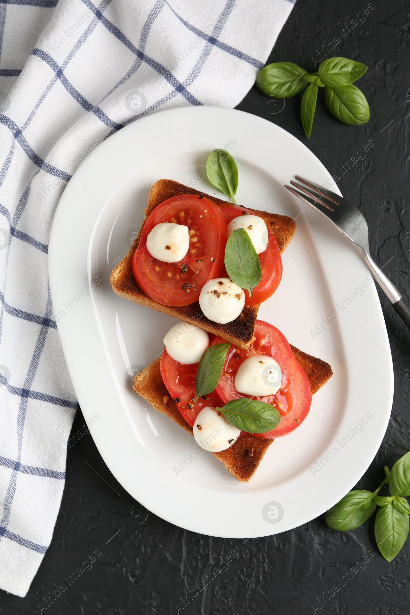Tasty sandwiches with mozzarella cheese, tomatoes, basil and fork on dark textured table, flat lay Photo of Tasty sandwiches with mozzarella cheese, tomatoes, basil and fork on dark textured table, flat lay