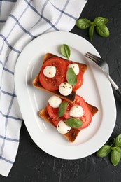 Photo of Tasty sandwiches with mozzarella cheese, tomatoes, basil and fork on dark textured table, flat lay
