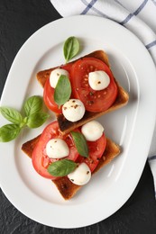 Photo of Tasty sandwiches with mozzarella cheese, tomatoes and basil on dark textured table, top view
