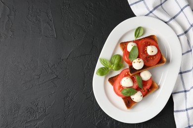 Photo of Tasty sandwiches with mozzarella cheese, tomatoes and basil on dark textured table, top view. Space for text