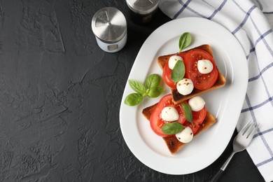 Photo of Tasty sandwiches with mozzarella cheese, tomatoes, basil and fork on dark textured table, flat lay. Space for text