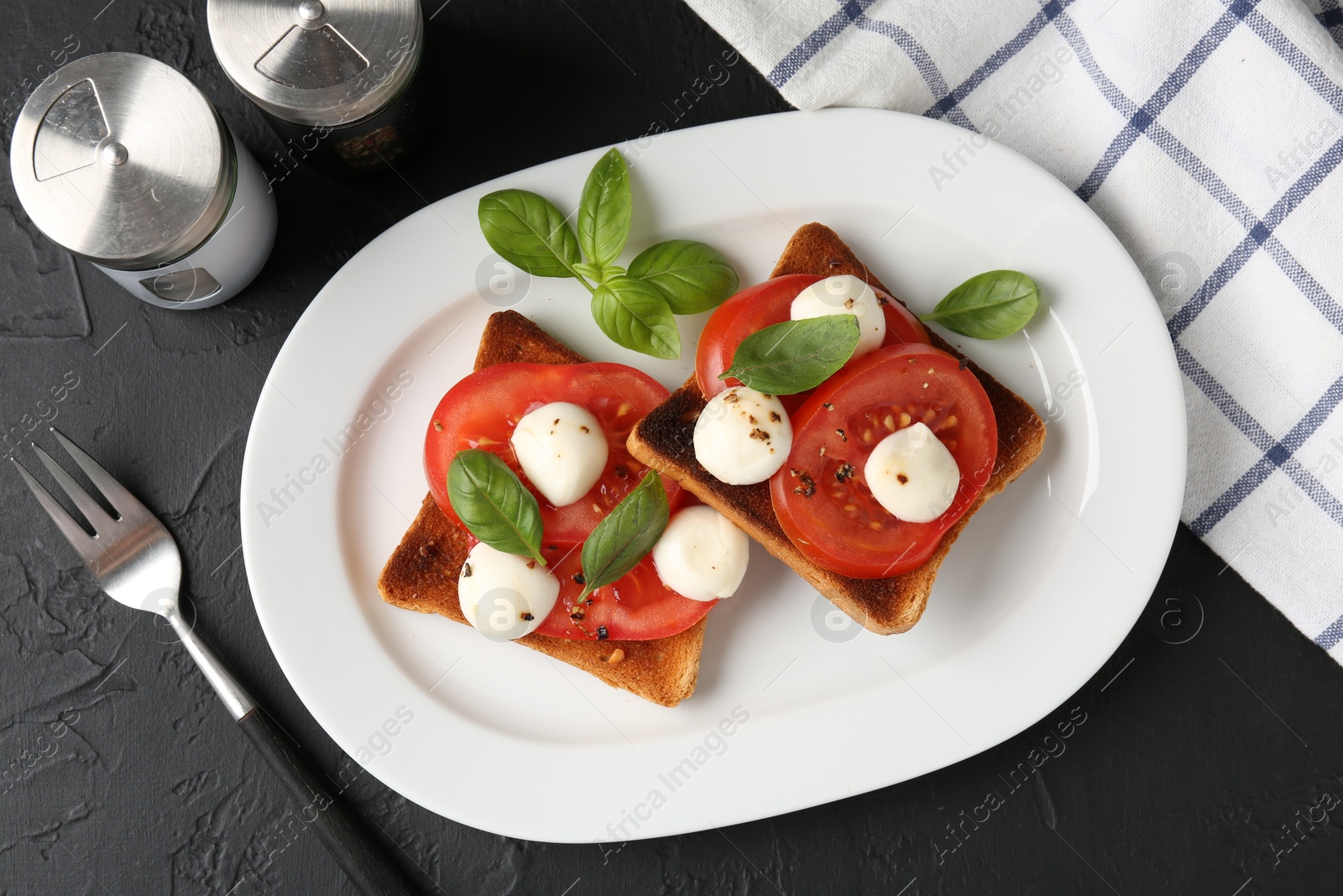 Tasty sandwiches with mozzarella cheese, tomatoes, basil and fork on dark textured table, flat lay Photo of Tasty sandwiches with mozzarella cheese, tomatoes, basil and fork on dark textured table, flat lay