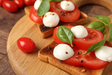 Photo of Tasty sandwiches with mozzarella cheese, tomatoes and basil on wooden table, closeup