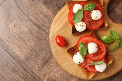 Photo of Tasty sandwiches with mozzarella cheese, tomatoes and basil on wooden table, top view. Space for text