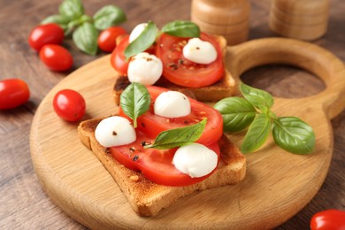 Photo of Tasty sandwiches with mozzarella cheese, tomatoes and basil on wooden table, closeup