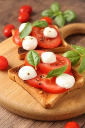 Photo of Tasty sandwiches with mozzarella cheese, tomatoes and basil on wooden table, closeup