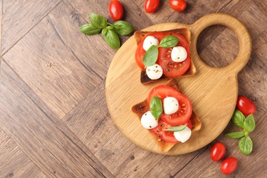 Photo of Tasty sandwiches with mozzarella cheese, tomatoes and basil on wooden table, flat lay. Space for text