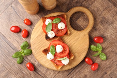 Photo of Tasty sandwiches with mozzarella cheese, tomatoes and basil on wooden table, flat lay