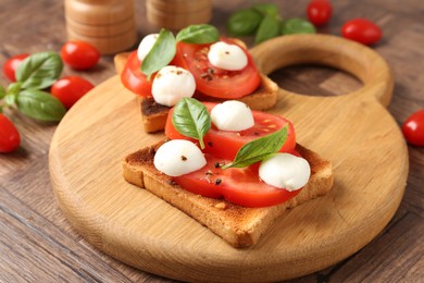 Photo of Tasty sandwiches with mozzarella cheese, tomatoes and basil on wooden table, closeup