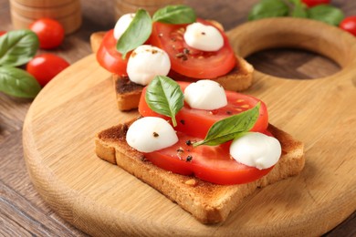 Photo of Tasty sandwiches with mozzarella cheese, tomatoes and basil on wooden table, closeup