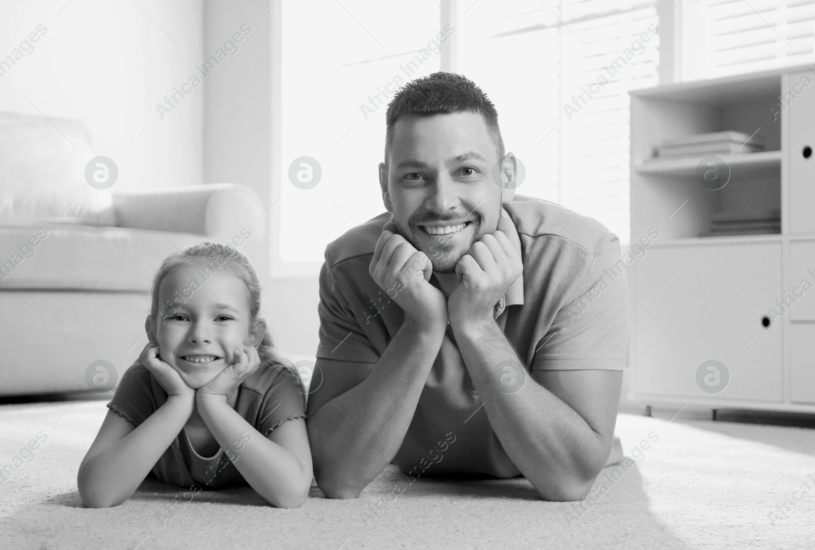 Dad with his daughter lying on floor at home. Black-and-white toning Image of Dad with his daughter lying on floor at home. Black-and-white toning