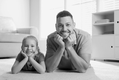 Image of Dad with his daughter lying on floor at home. Black-and-white toning