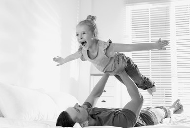 Image of Dad with his daughter having fun at home. Black-and-white toning