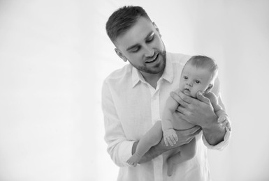Image of Dad holding his baby daughter on light background. Black-and-white toning