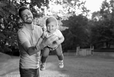 Image of Dad with his baby daughter having fun outdoors. Black-and-white toning