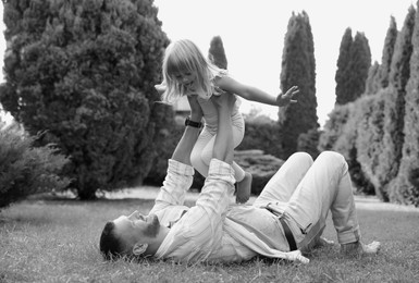 Image of Dad with his daughter having fun outdoors. Black-and-white toning