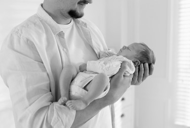Image of Dad holding his baby daughter at home, closeup. Black-and-white toning