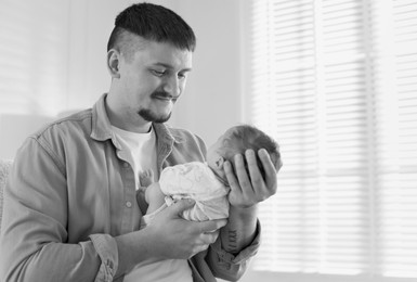 Image of Dad holding his baby daughter at home. Black-and-white toning