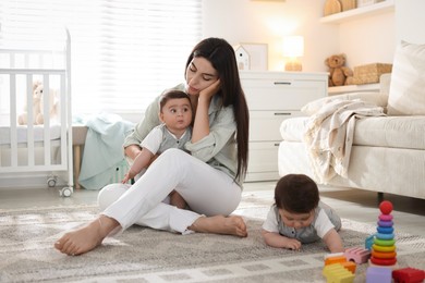 Photo of Woman suffering from postpartum depression with her little children at home