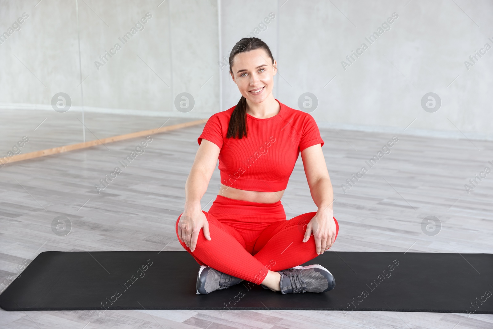 Photo of Beautiful woman sitting on fitness mat in gym