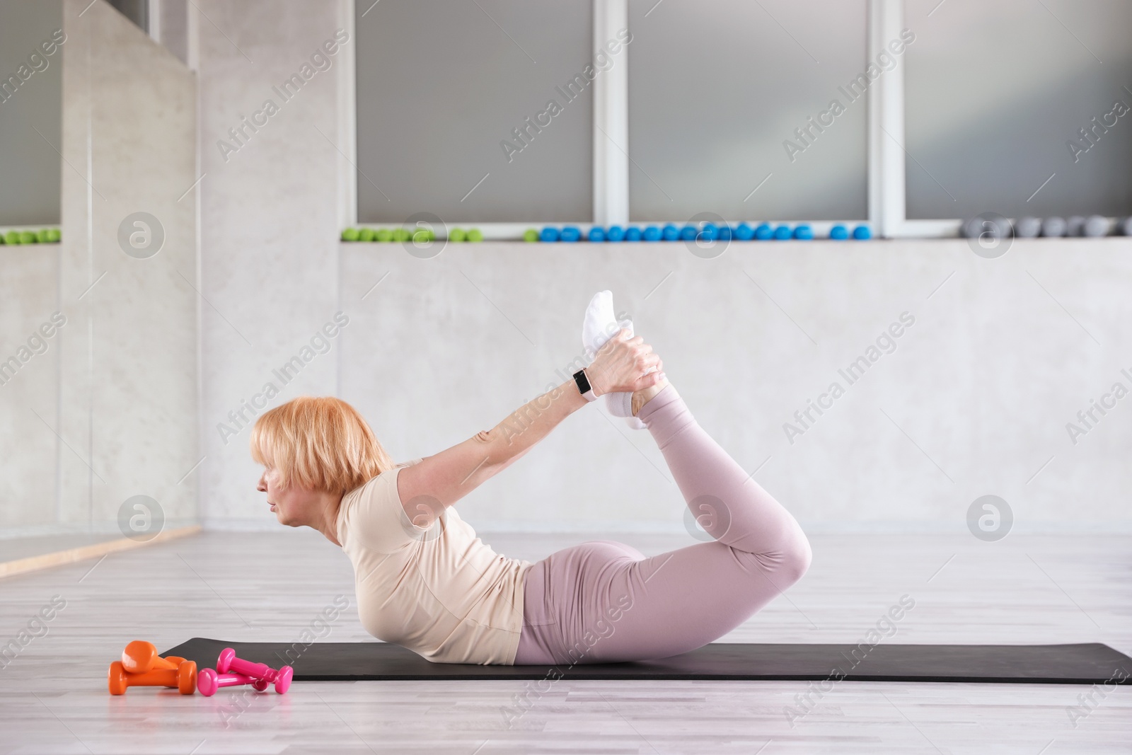 Senior woman exercising on fitness mat in gym Photo of Senior woman exercising on fitness mat in gym
