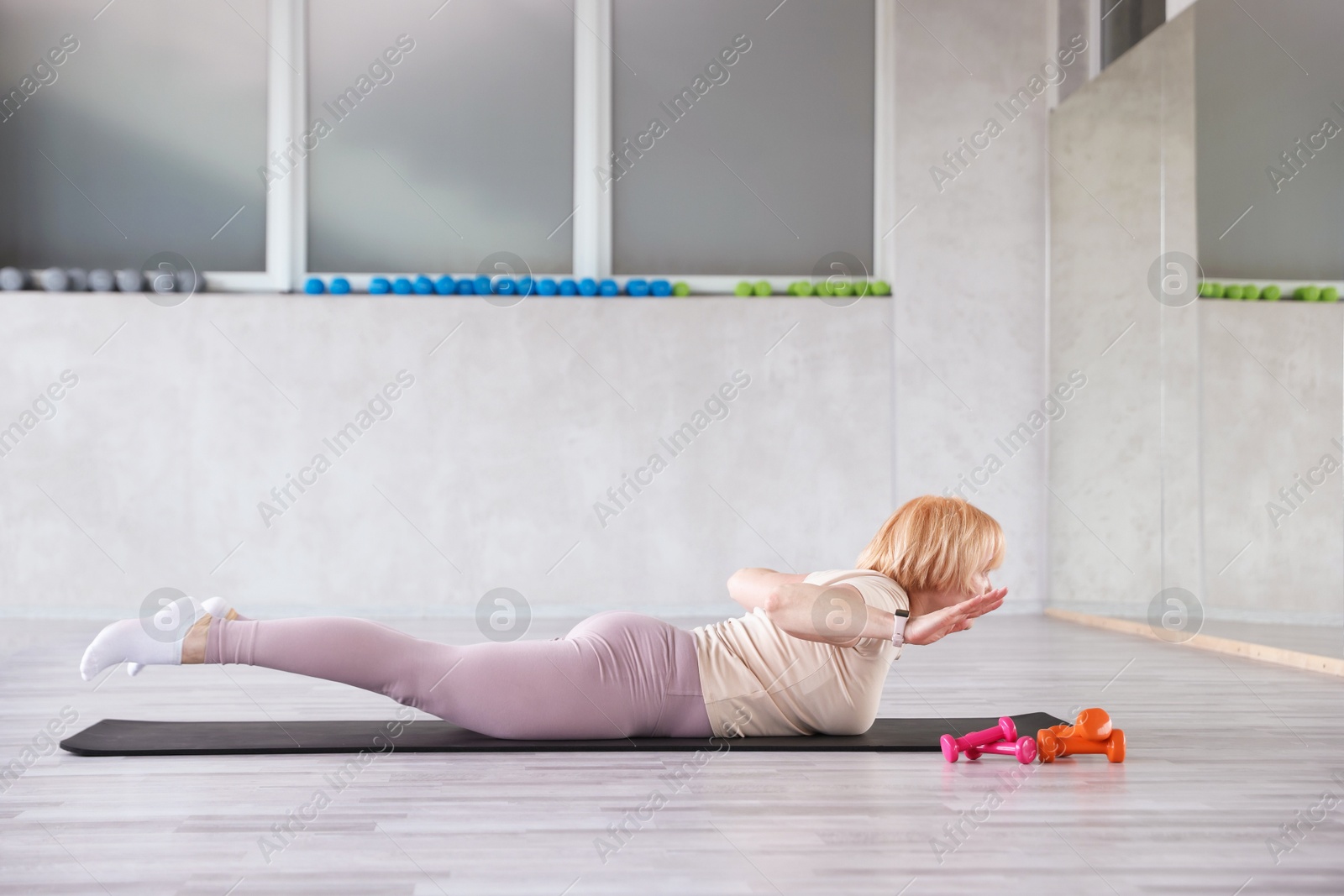 Senior woman exercising on fitness mat in gym Photo of Senior woman exercising on fitness mat in gym