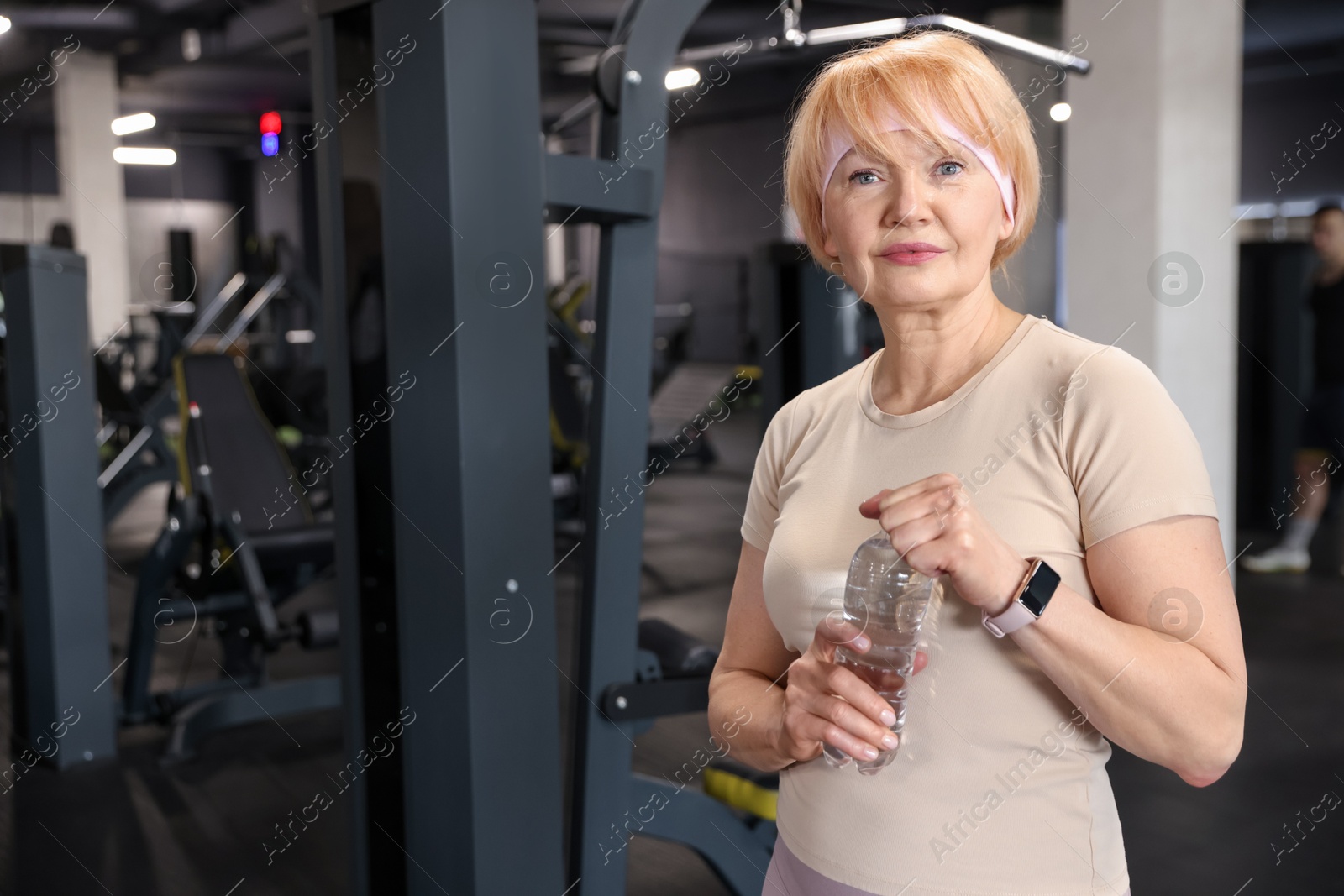 Senior woman with bottle of water in gym Photo of Senior woman with bottle of water in gym