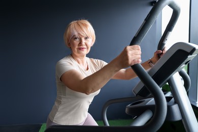 Photo of Senior woman training on elliptical machine in gym