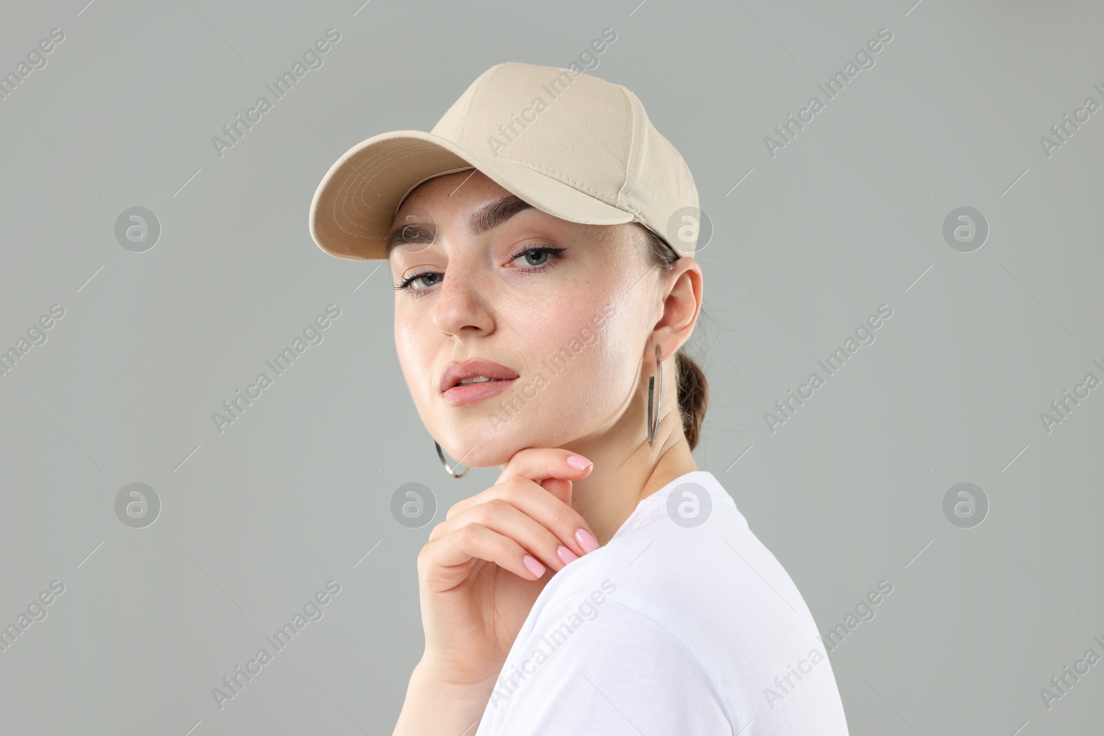 Beautiful woman in stylish baseball hat on grey background, closeup Photo of Beautiful woman in stylish baseball hat on grey background, closeup