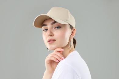Photo of Beautiful woman in stylish baseball hat on grey background, closeup