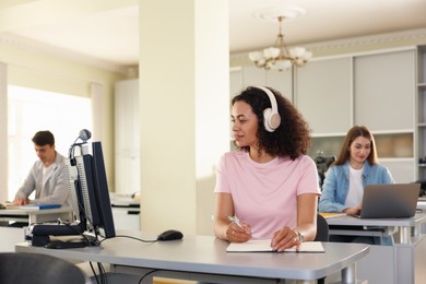 Photo of People working at desks in library, selective focus