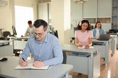 Photo of People studying at desks in public library, selective focus