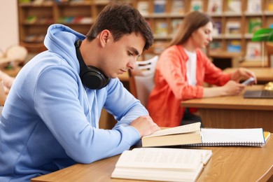 Photo of People studying at desks in public library, selective focus