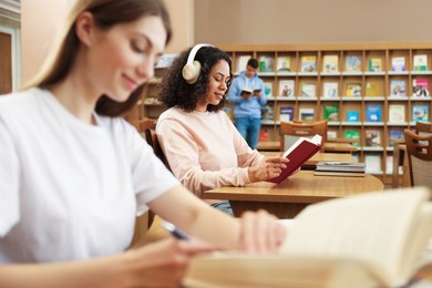 Photo of People studying in public library, selective focus
