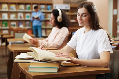 Photo of People studying at desks in public library, selective focus
