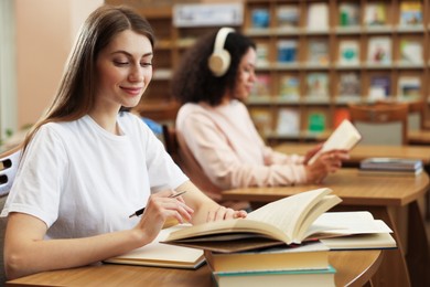 Photo of People studying at desks in public library, selective focus