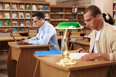 Photo of People studying at desks in public library, selective focus