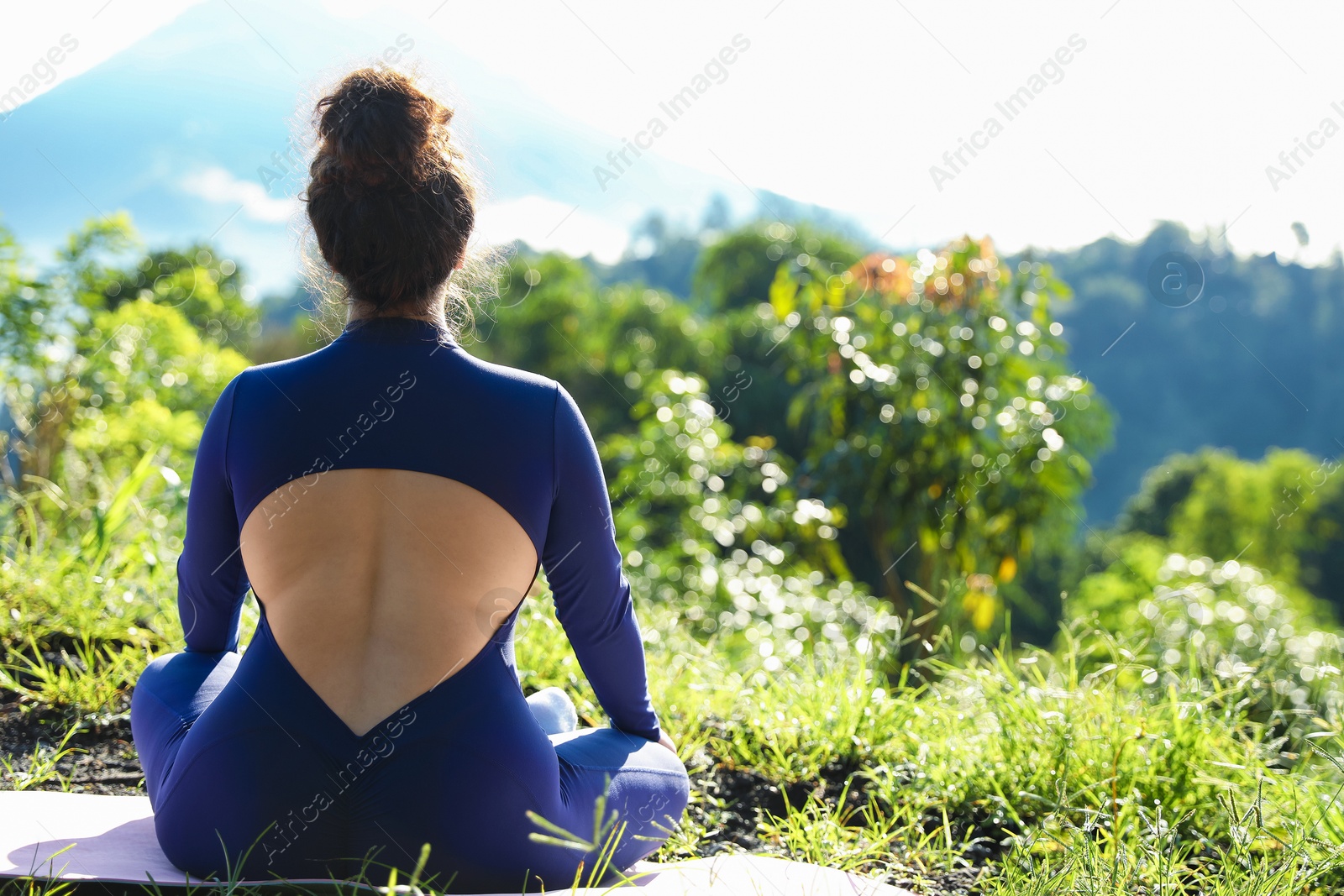 Woman meditating on yoga mat outdoors, back view. Space for text Photo of Woman meditating on yoga mat outdoors, back view. Space for text