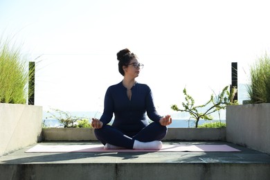 Photo of Woman meditating on yoga mat at balcony