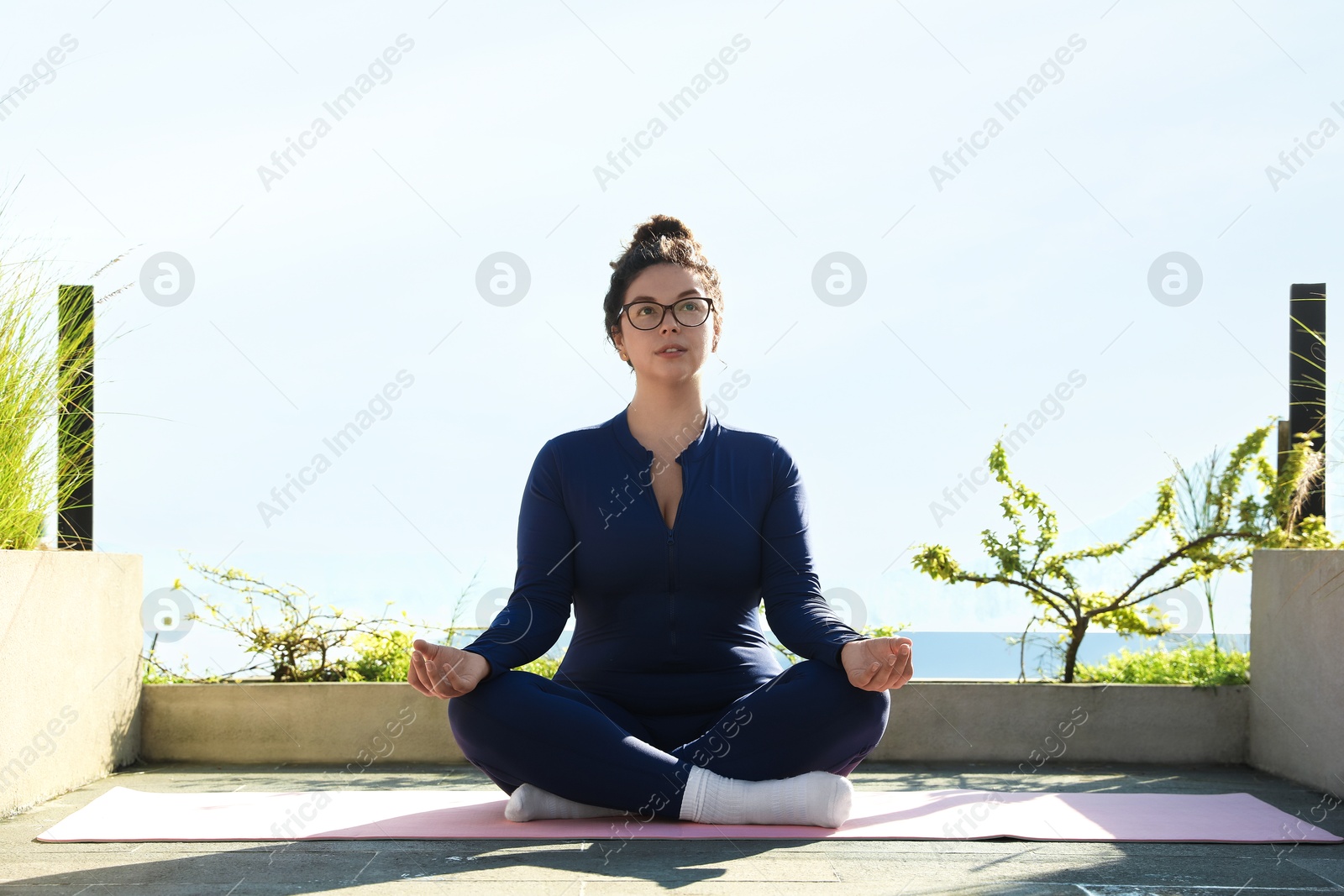 Woman meditating on yoga mat at balcony Photo of Woman meditating on yoga mat at balcony